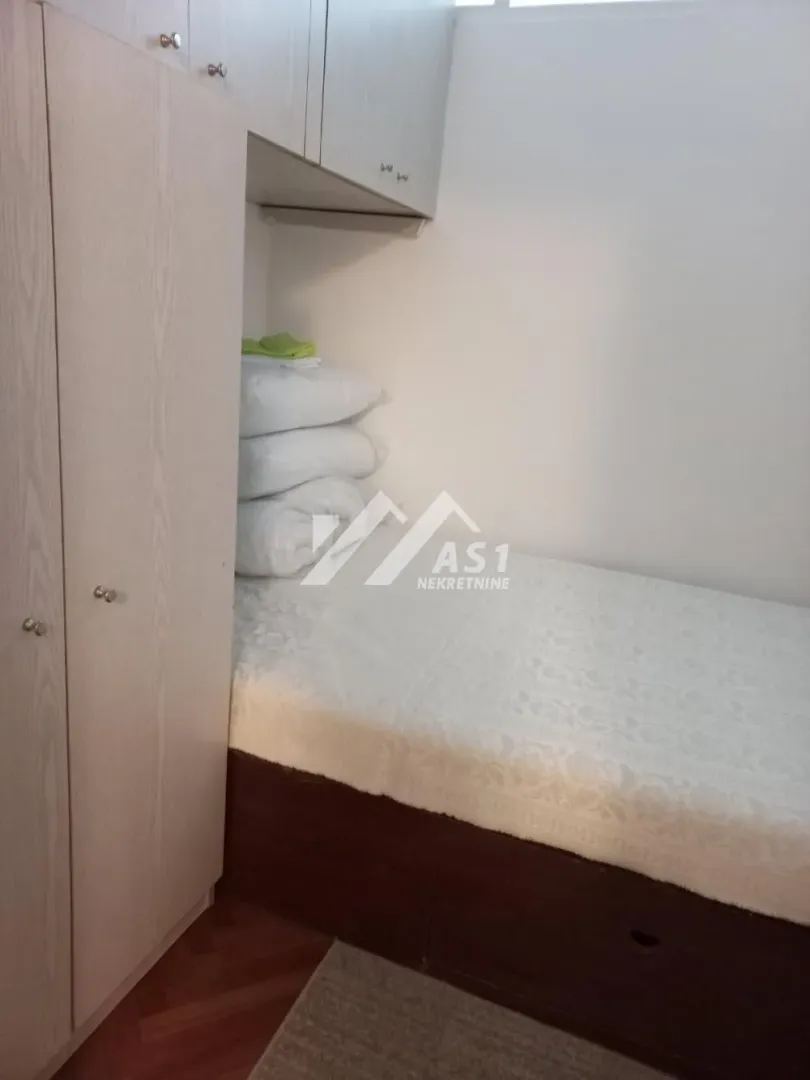 Manja spavaća soba sa krevetom i ugradnim ormanom.