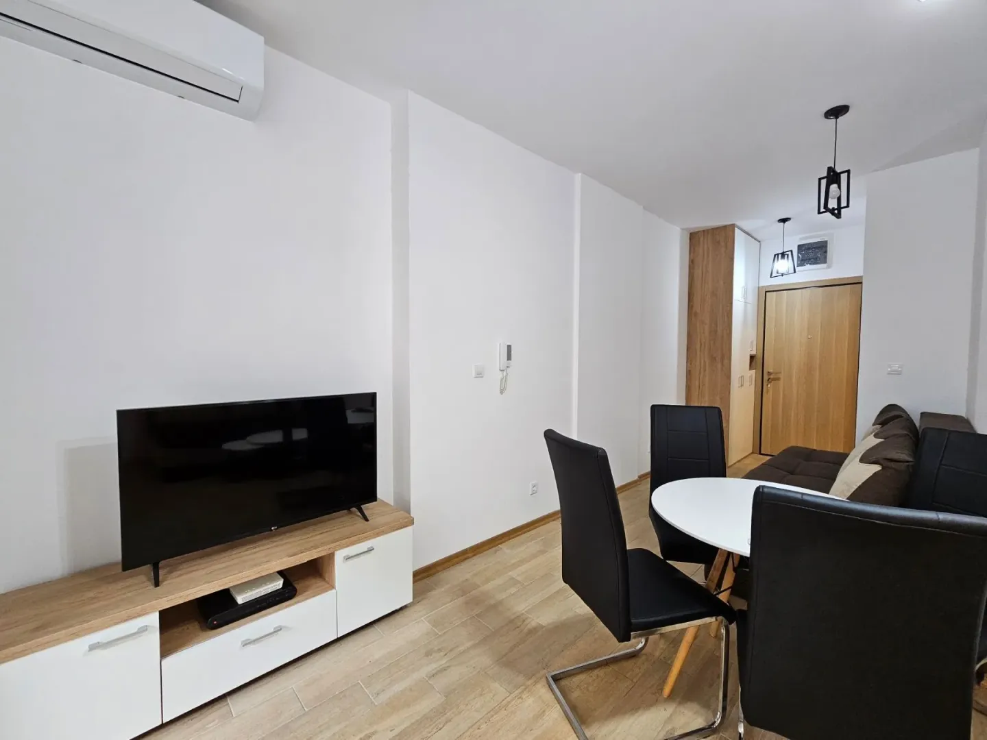 Living room with a sofa, TV unit, and dining table.