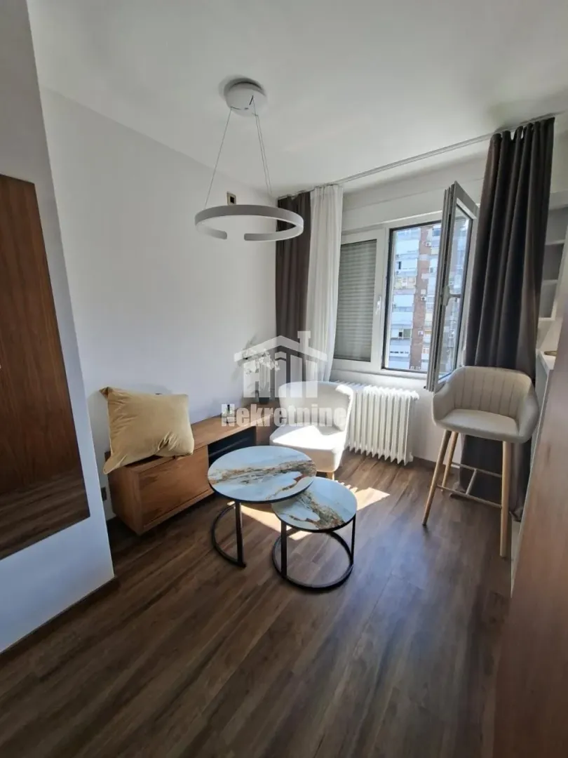 Smaller living room with seating, coffee tables, and a window.