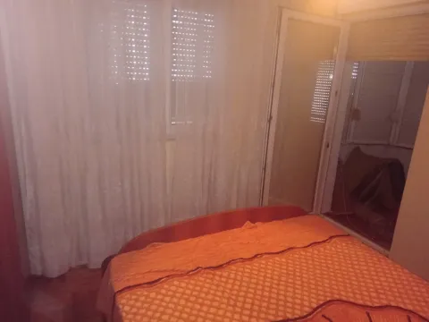 Spavaća soba sa narandžastim prekrivačem na krevetu i izlazom na terasu. - image 7