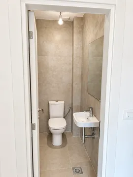 Pogled iz predsoblja na manje kupatilo sa WC šoljom i umivaonikom. - image 15
