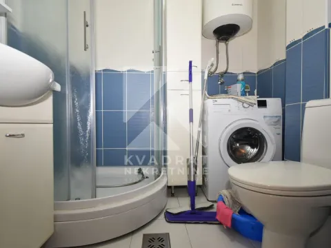 Bathroom equipped with a shower cabin, washbasin, toilet, and washing machine. - image 13