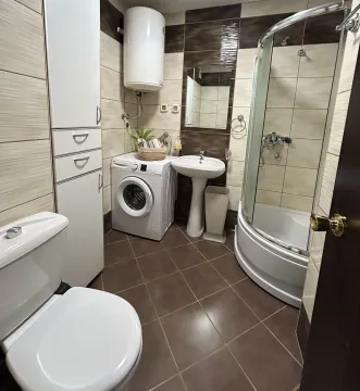 Kupatilo opremljeno tuš kabinom, umivaonikom, WC šoljom, mašinom za veš i bjelim ormarićem. - image 8