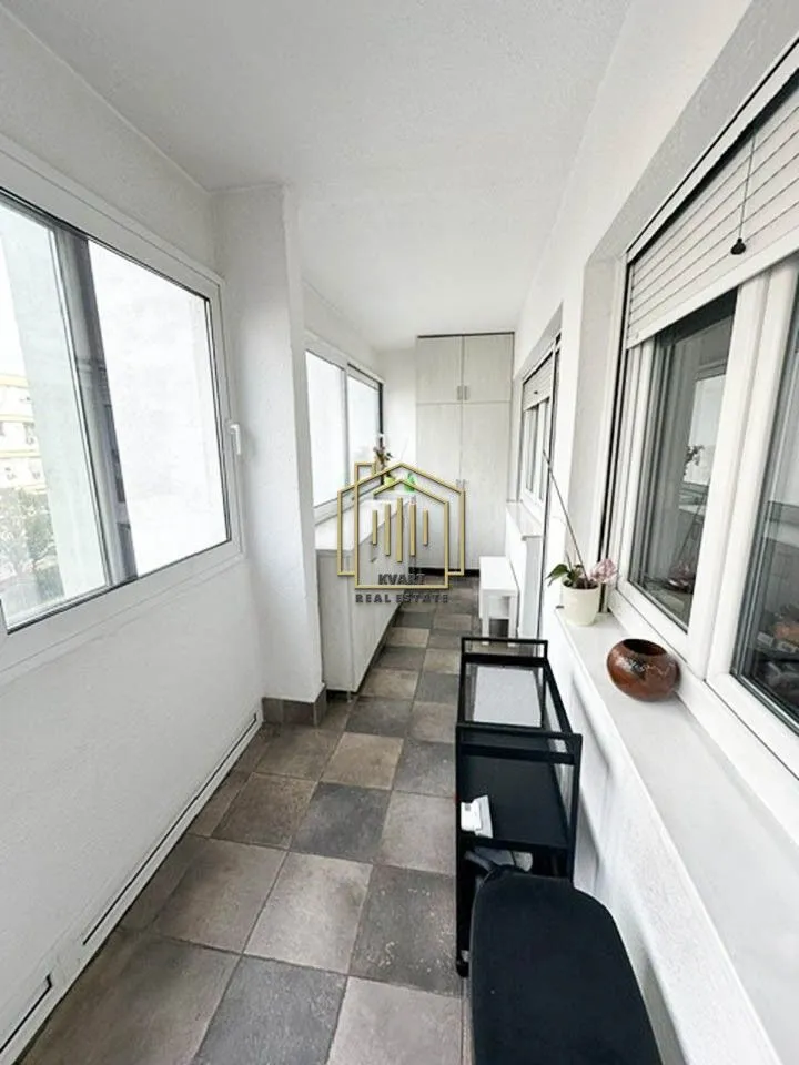 Zastakljeni balkon sa pločicama na podu i prozorima duž cijele dužine.