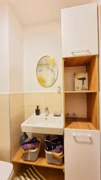 Bathroom with a washbasin, mirror and wooden storage units. - image 9
