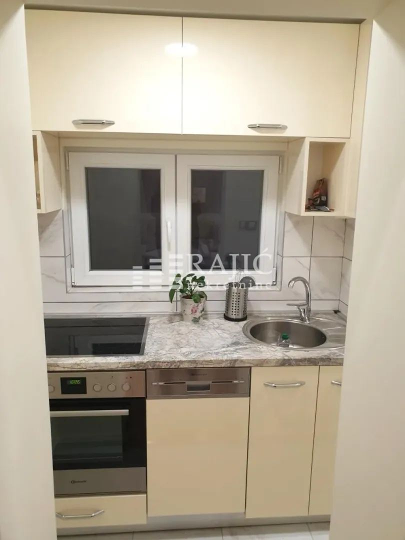 Small kitchen with built-in appliances, sink, and window.