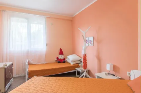 Dvosobna spavaća soba sa krevetima i narandžastim zidovima. - image 4