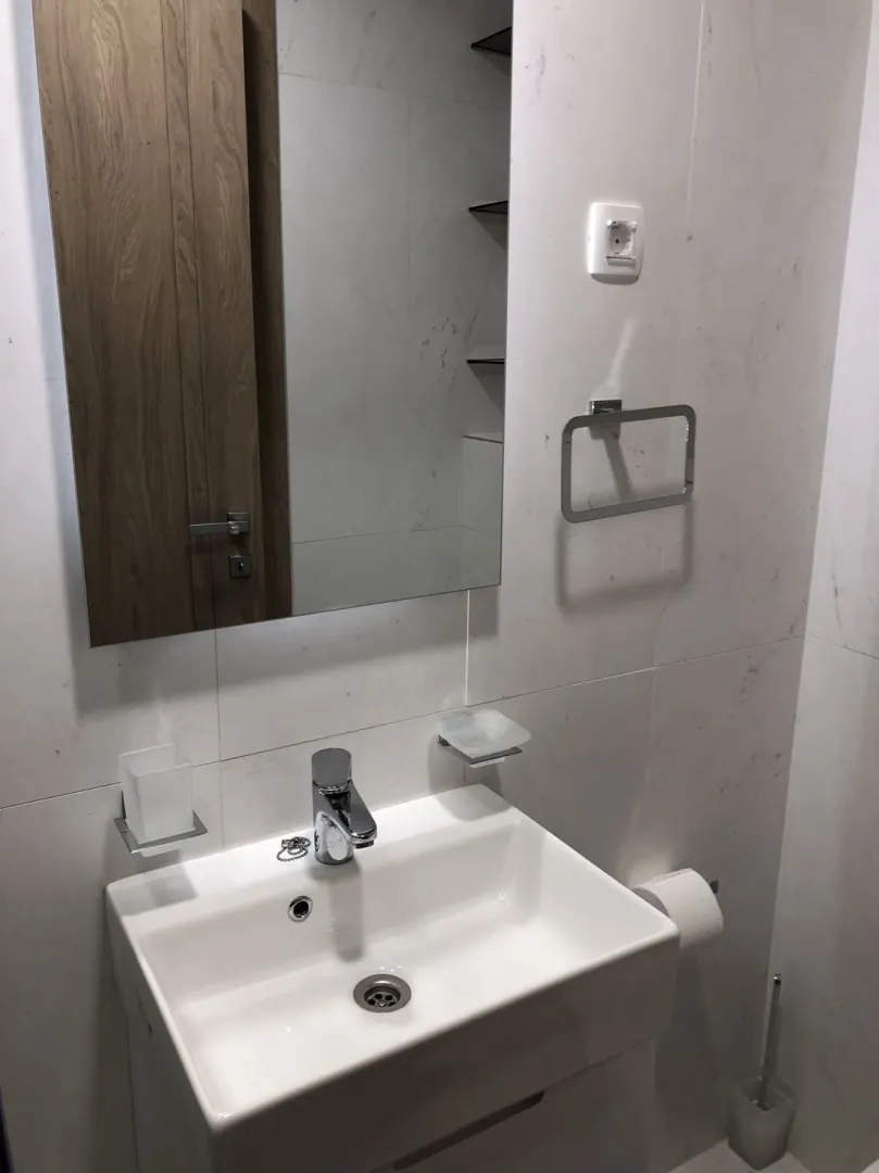 Modern sink with a mirror in a bathroom with light tiles.
