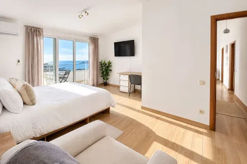 Spacious bedroom with a double bed, desk, and access to a terrace with a sea view. - image 7