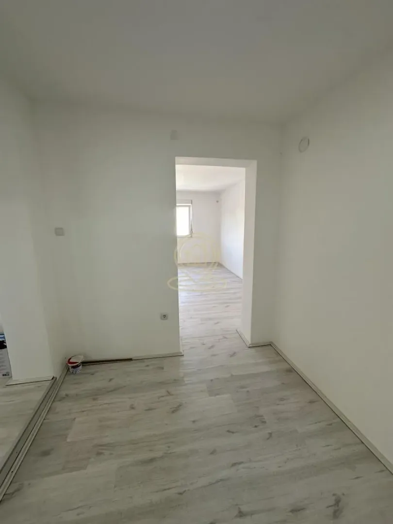 Prazna prostorija sa laminatnim podom i prolazom u drugu sobu.