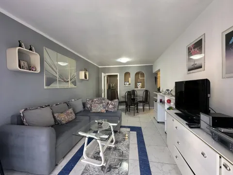 Living room with a sectional sofa, TV, and a dining area in the background. - image 14