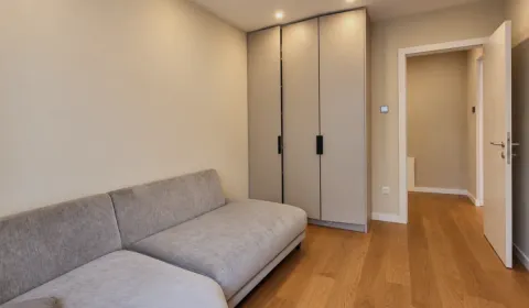 Small bedroom with a gray sofa bed, built-in wardrobe, and wooden flooring. - image 11