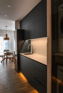 Modern kitchen with dark cabinets and a dining area in the background. - image 3