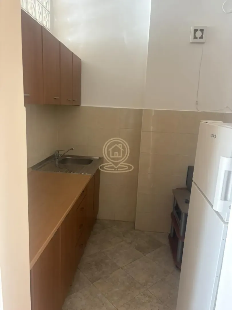 Small kitchen with wooden cabinets and a refrigerator.