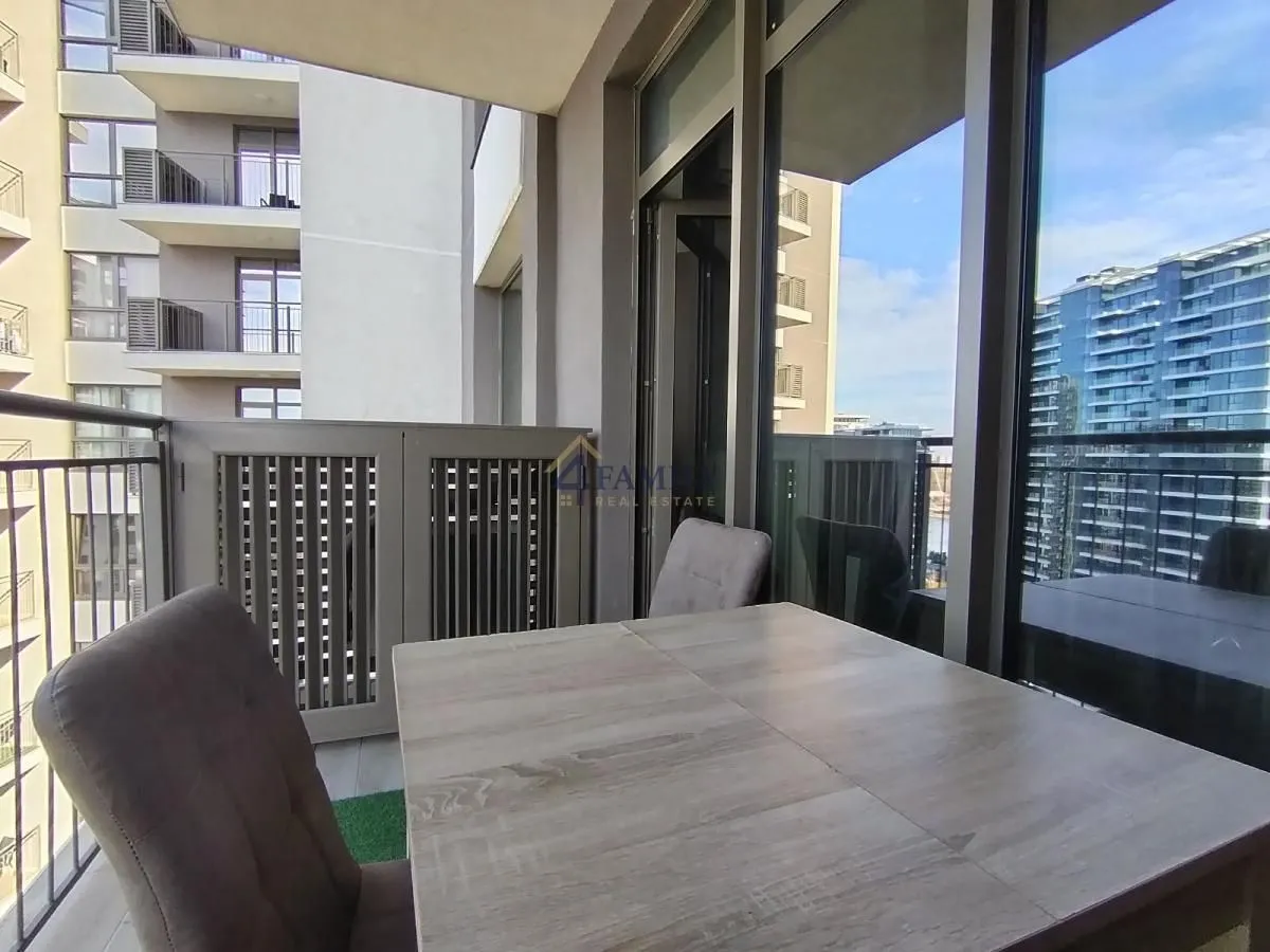 Spacious covered terrace with a table and chairs and a view of buildings.