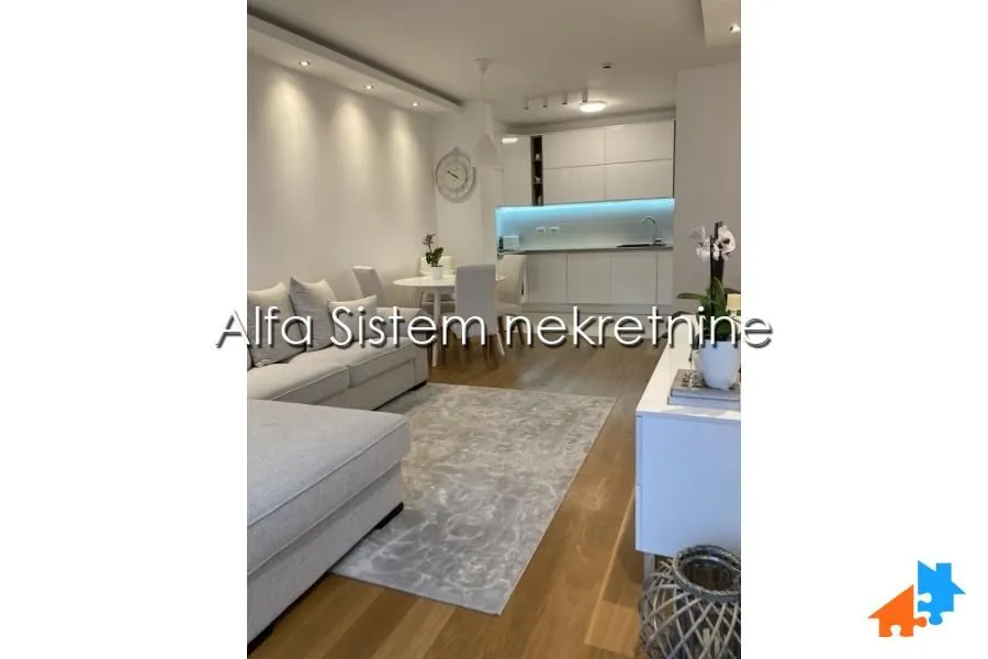 Living room with a sofa set, dining area, and fitted kitchen in the background.