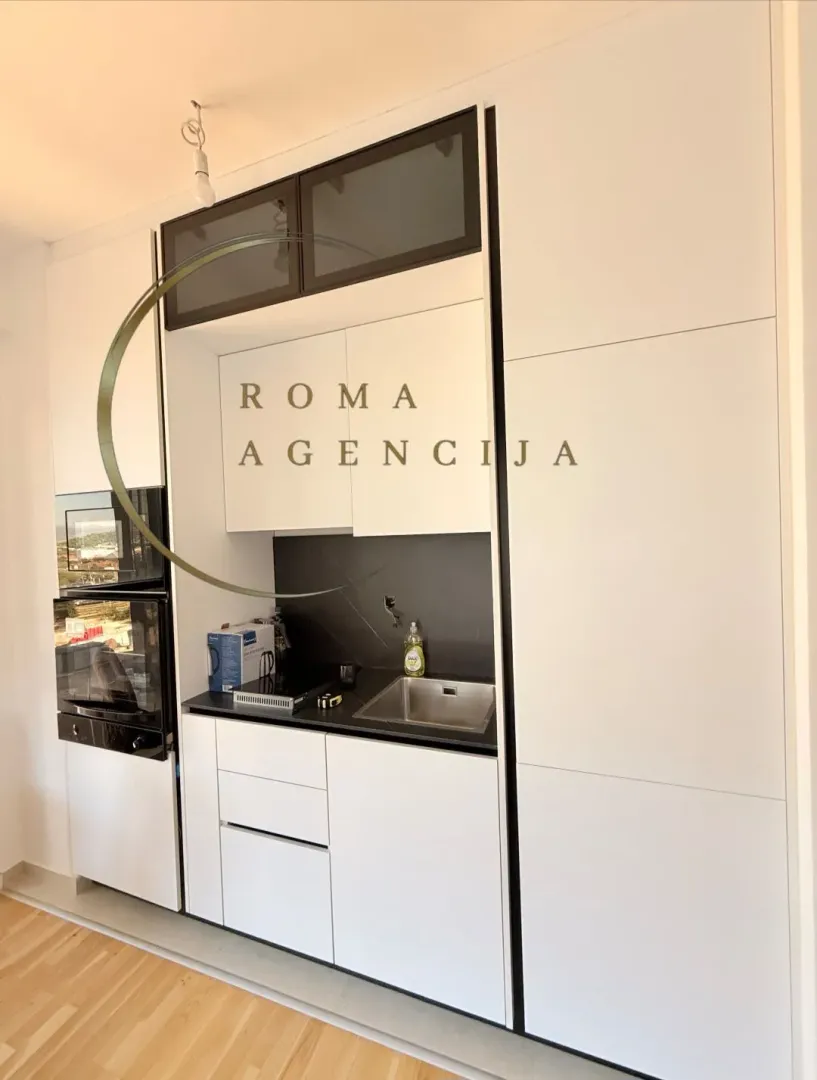 Modern white kitchen with black details and built-in appliances.