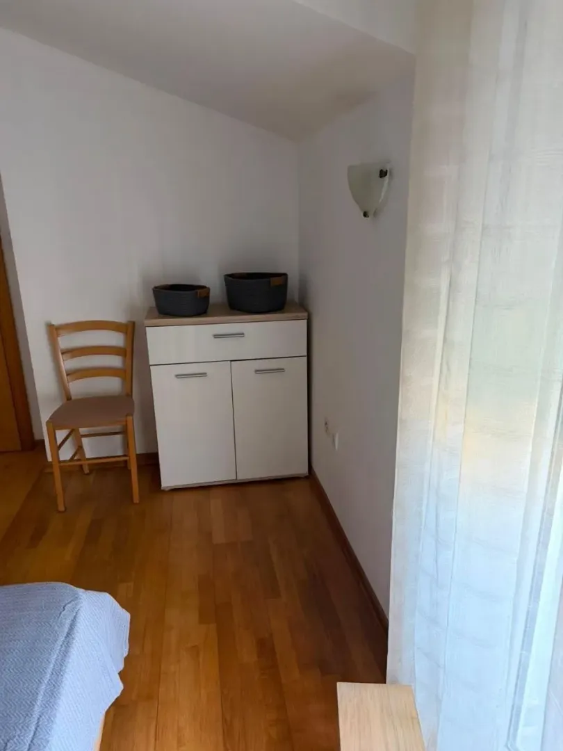 Dio spavaće sobe sa manjom komodom, stolicom i drvenim podom.