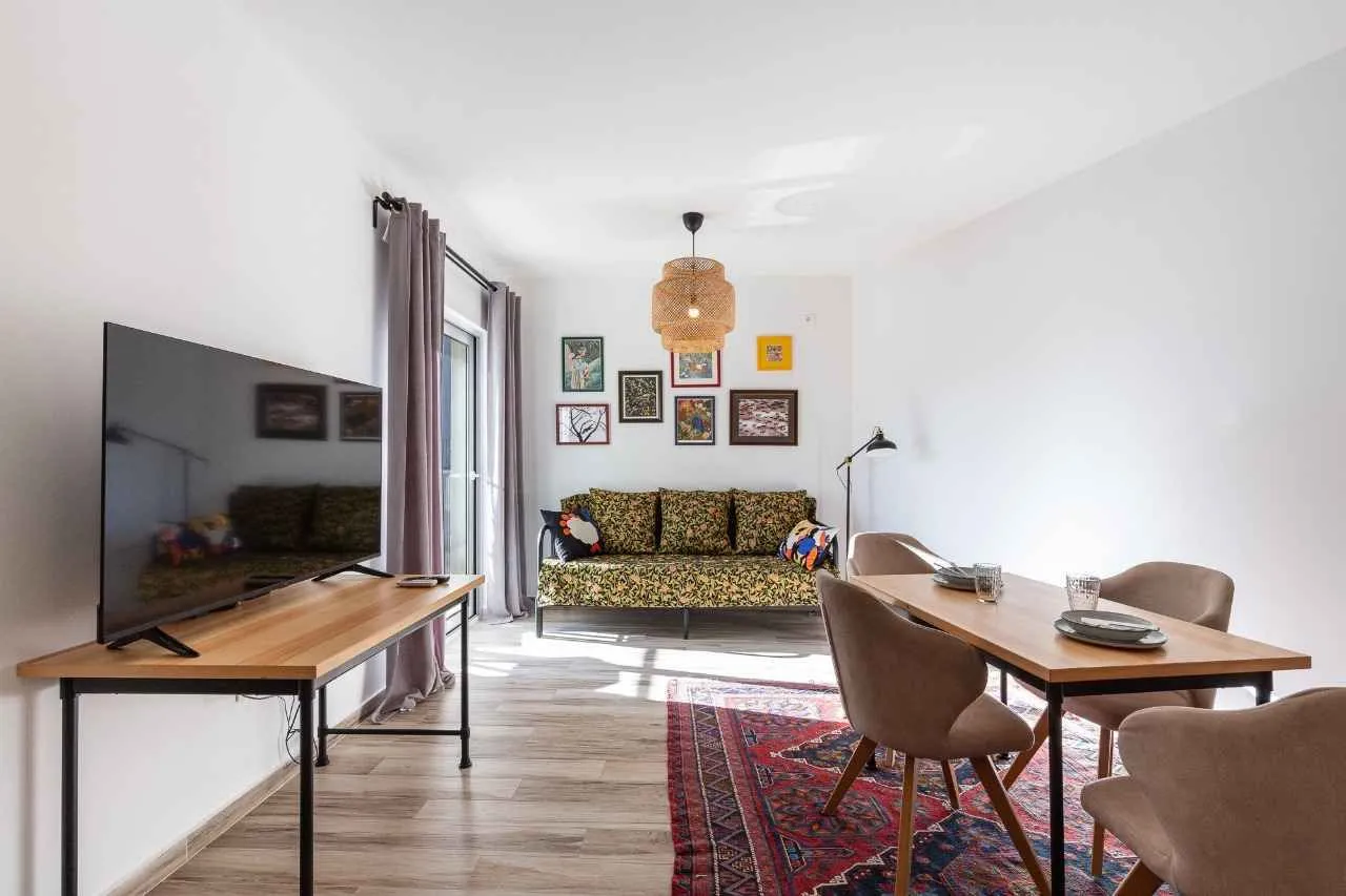 Living room with a sofa set, television, and dining table.