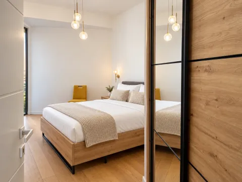 Modern bedroom with a double bed, wooden flooring, and a mirrored fitted wardrobe. - image 9