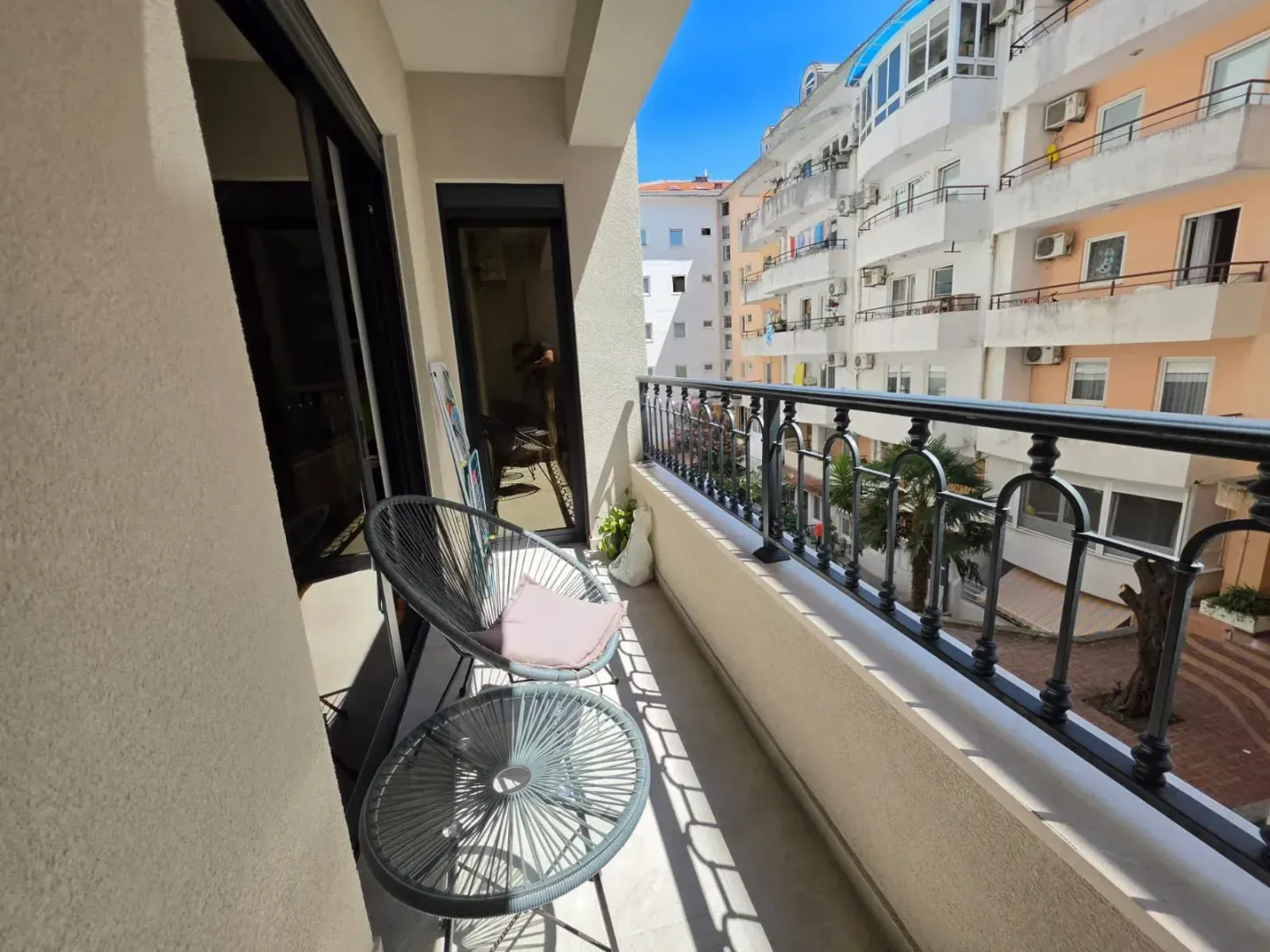 Namješten balkon sa garniturom za sjedenje i pogledom na okolne zgrade.