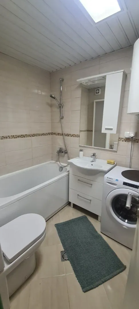 Svijetlo kupatilo sa kadom, lavaboom i veš mašinom.