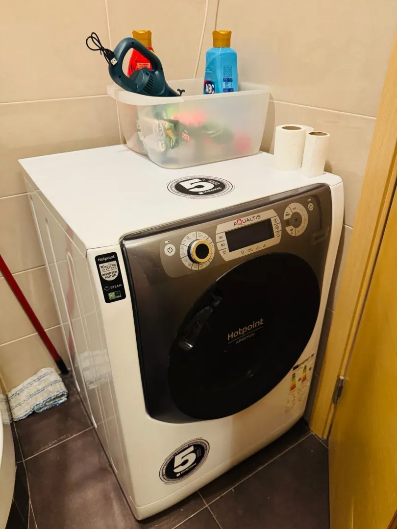 Bathroom with a washing machine and cleaning supplies.