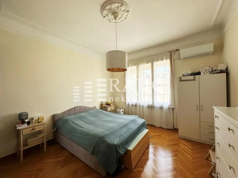 Furnished bedroom with a double bed, wardrobe, and parquet flooring.