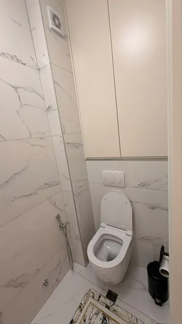 Small modernly equipped bathroom with white tiles and built-in elements.