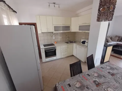 Kitchen equipped with white cabinetry, built-in appliances, and a dining table in the foreground. - image 4