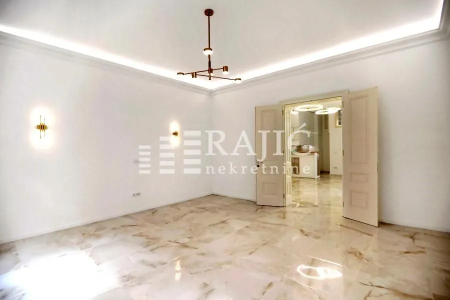 Empty living room with marble flooring and modern lighting.