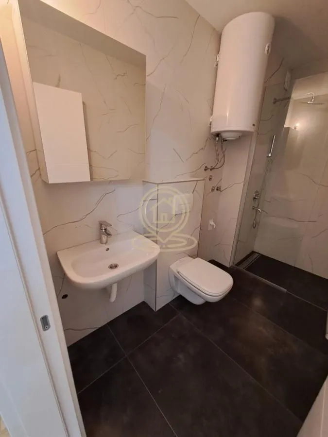 Moderno kupatilo sa tuš kabinom, umivaonikom i wc šoljom.
