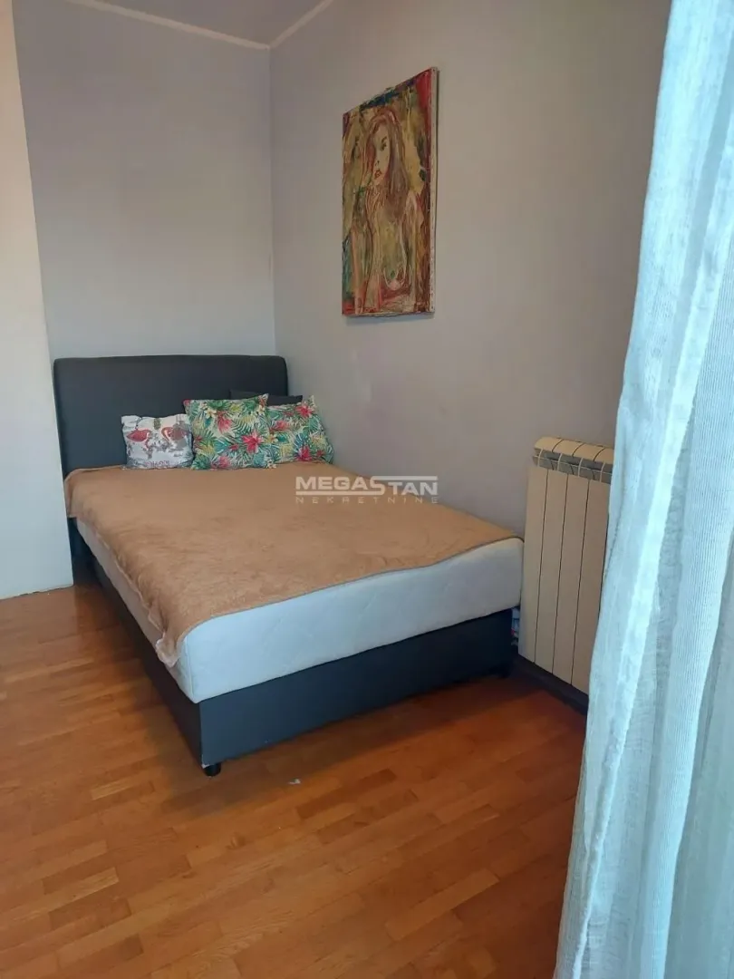 Furnished bedroom with a double bed and a painting on the wall.