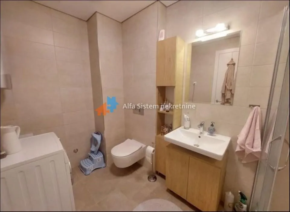Fully equipped bathroom with a sink, toilet, cabinet, and shower cabin.