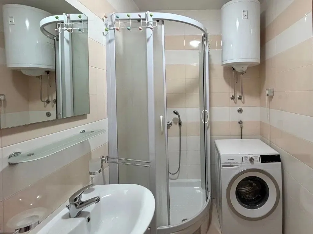 Bathroom equipped with a shower cabin, sink, and washing machine.