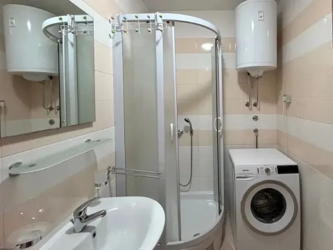 Bathroom equipped with a shower cabin, sink, and washing machine. - image 7