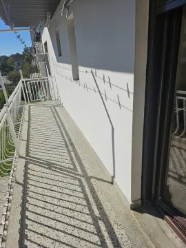 Uski spoljni balkon sa metalnom ogradom obasjan suncem. - image 8