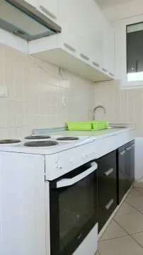 Manja kuhinja sa bijelim elementima, štednjakom i sudoperom pored prozora. - image 7