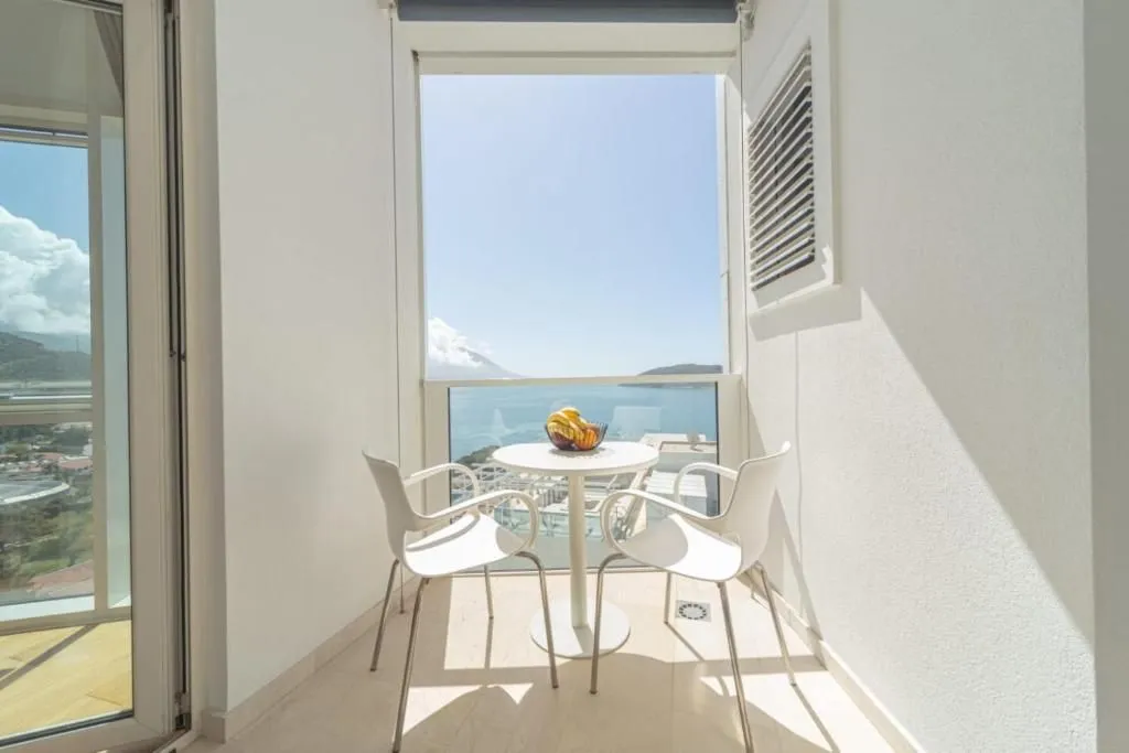 Bright and tidy balcony with a table, chairs, and a sea view.