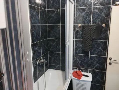 Bathroom with a bathtub tiled in dark tiles and a shower cabin. - image 6