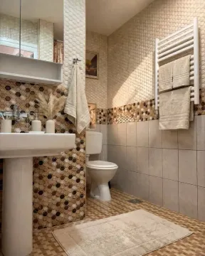 Renovated bathroom with a sink, toilet, and decorative tiles. - image 4