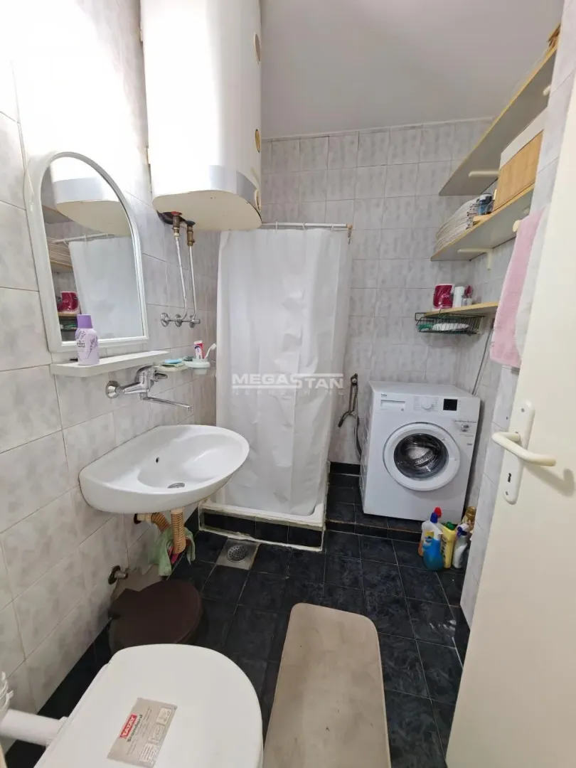 Manje kupatilo sa umivaonikom, tuš kabinom, WC šoljom i veš mašinom.