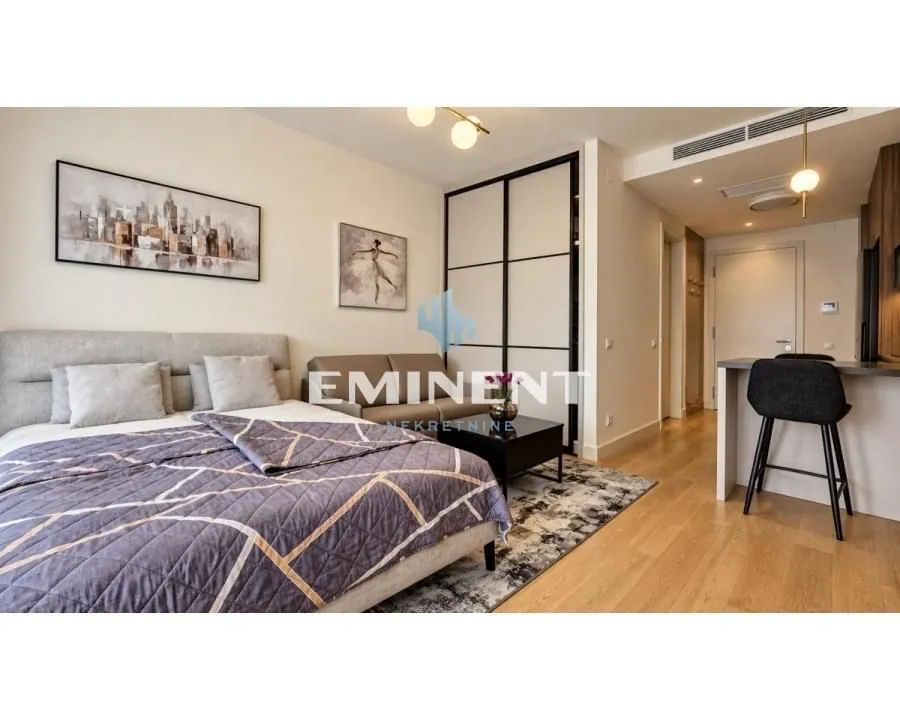 Furnished bedroom with a double bed, wardrobe, and a small sitting area.