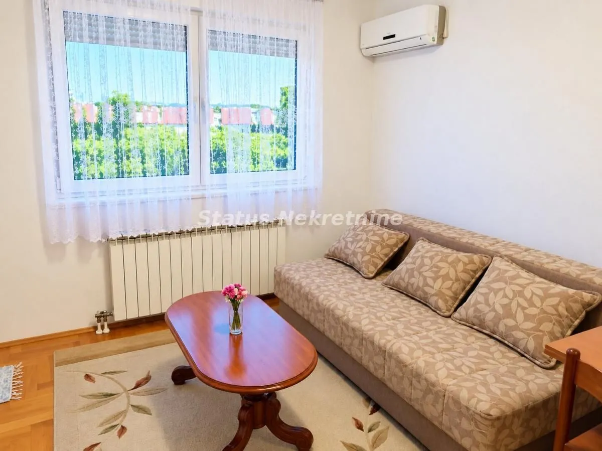 Living room with a sofa, coffee table, and air conditioning unit.
