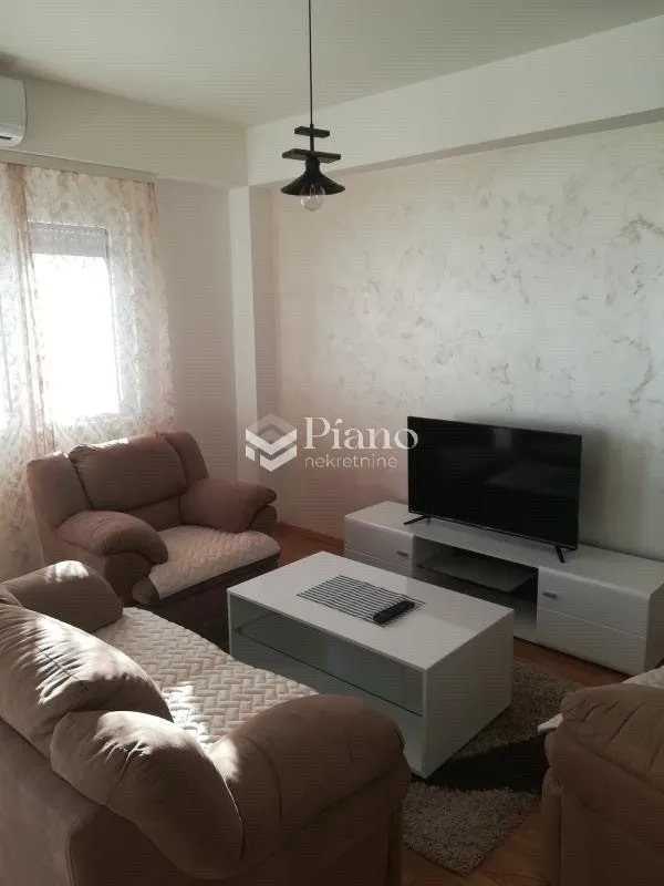 Living room with seating furniture, television and a white coffee table.