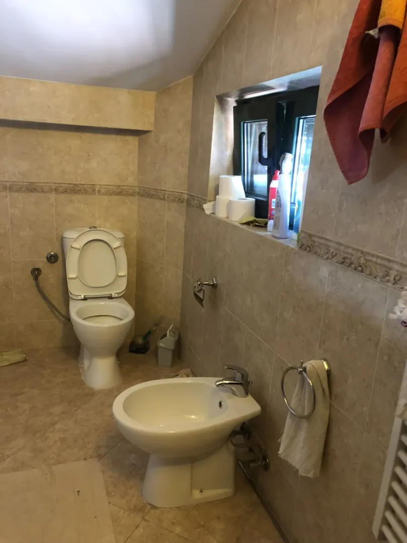 Bathroom with a bidet, toilet, and light-colored tiles.