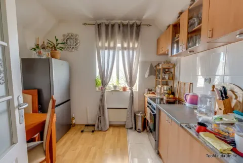 Kuhinja sa drvenim elementima, aparatima i trpezarijskim stolom. - image 13