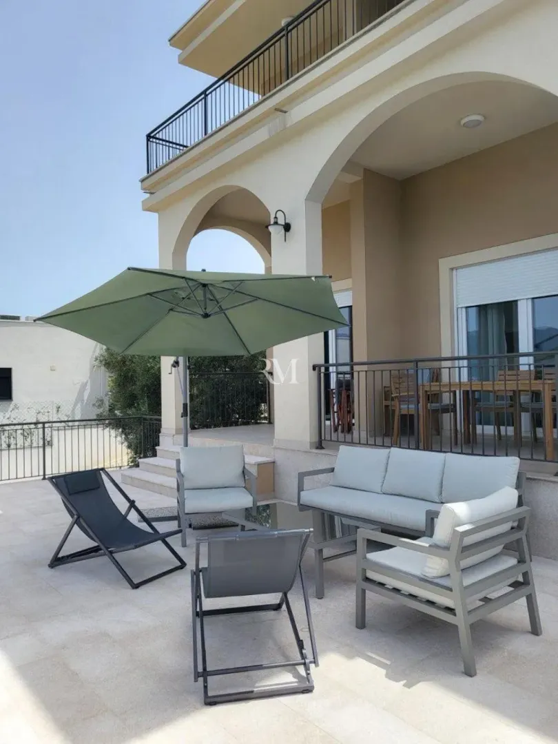Terrace with outdoor seating furniture and an umbrella in front of the house.