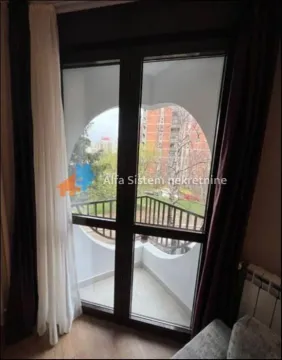 View through the balcony door with dark curtains towards the terrace and surrounding buildings. - image 13
