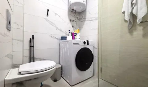 Small bathroom with a washing machine, toilet, and water heater. - image 9